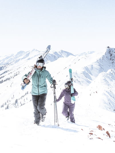 two skiers hiking up mountain
