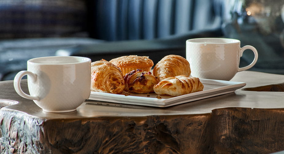 two coffee mugs and pastries on table