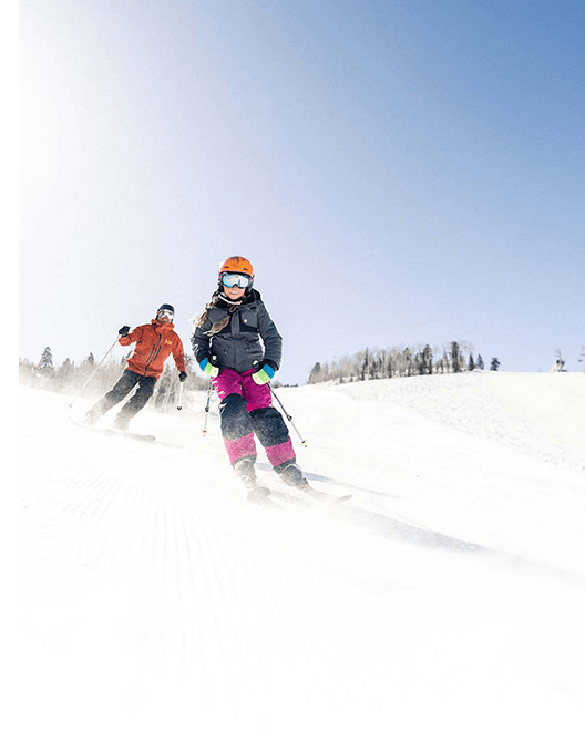 Two skiers shred down a groomer at Snowmass