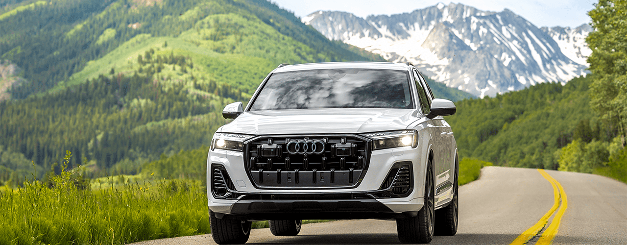 Audi drives through winding Snowmass roads, on a sunny summer day, with snowy peaks in the background